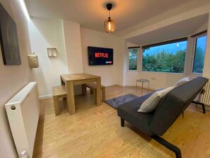 Relax in this stylish living room with a comfortable sofa, small table, and wall-mounted TV, offering a view of the outdoors.