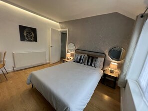 Cozy retreat with a large bed, bedside table, and wall-mounted mirror.