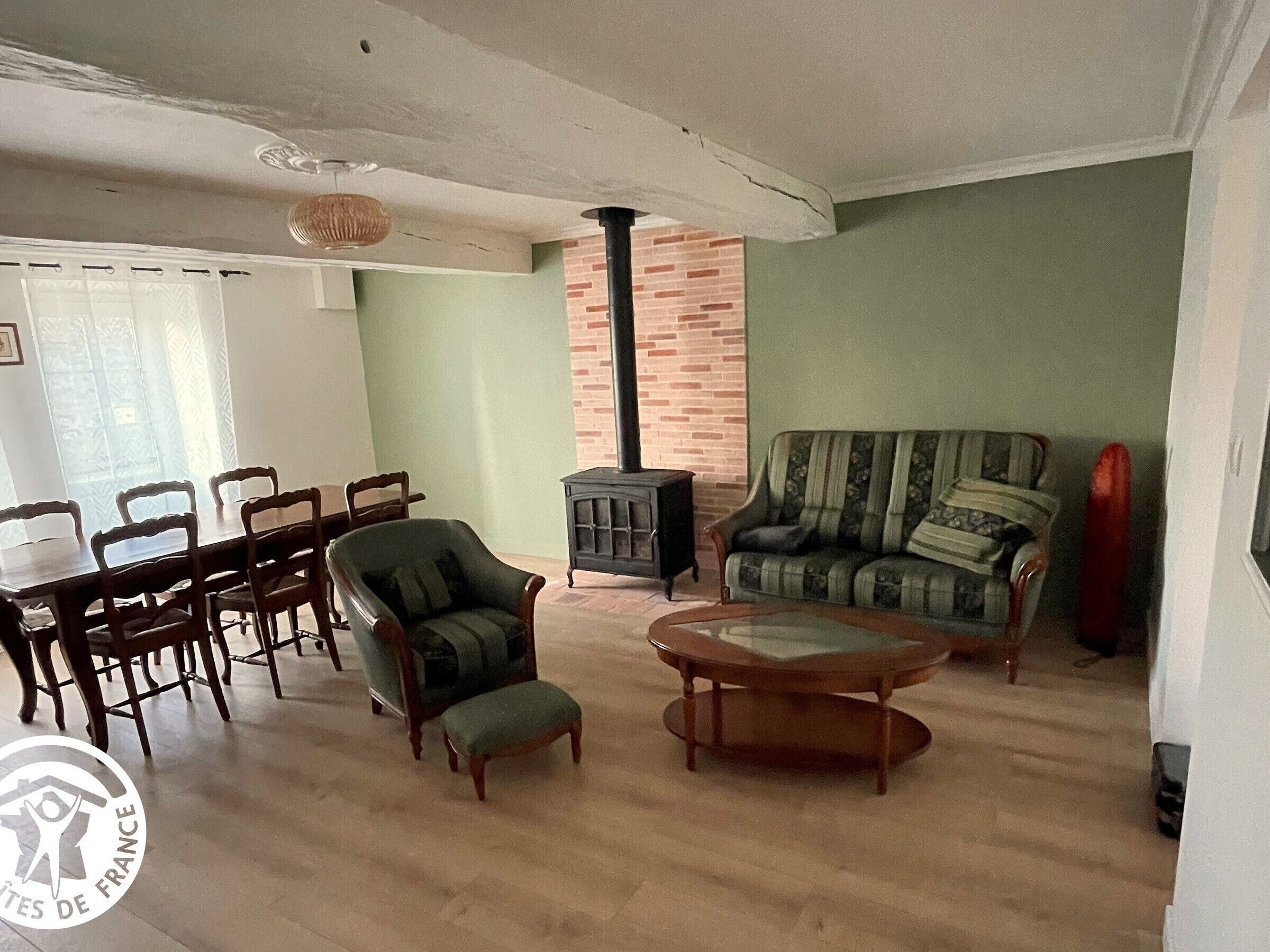 A living room with a dining area, a sofa, a chair, a table, and a fireplace.