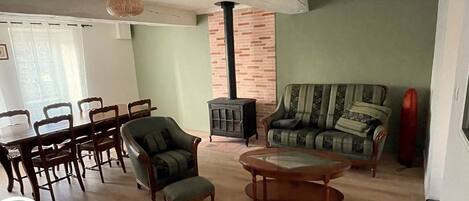 A living room with a dining area, a sofa, a chair, a table, and a fireplace.