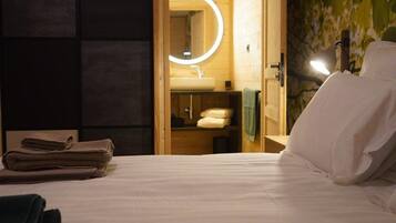 Ein Hotelzimmer mit einem Bett, einer Holztür zu einem Badezimmer und einem Spiegel mit Beleuchtung.