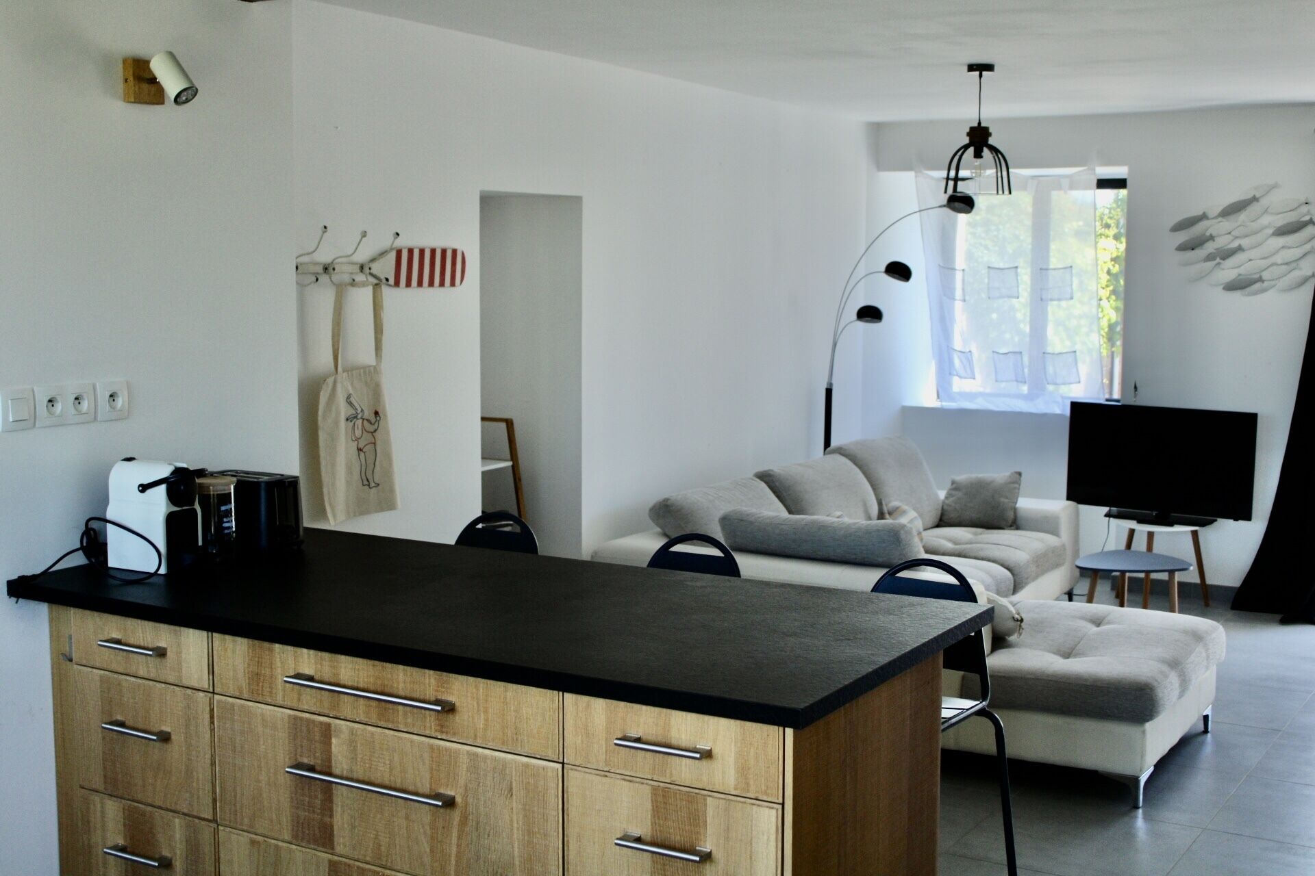 Un salon moderne avec un canapé, une table basse et un téléviseur. Il y a également un coin cuisine avec un comptoir et des placards.