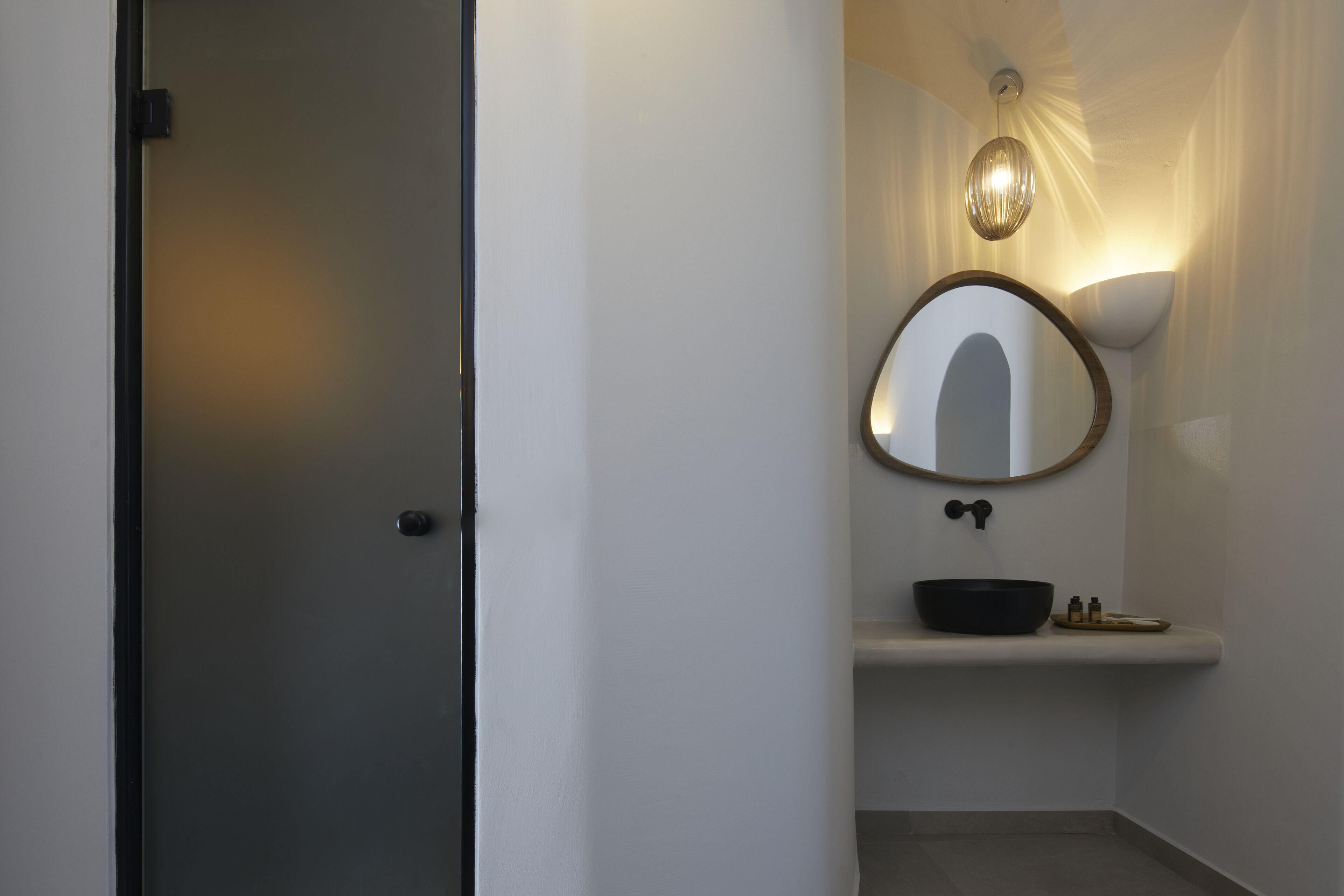 Een badkamer met een witte wastafel, een spiegel en een lamp boven de spiegel.