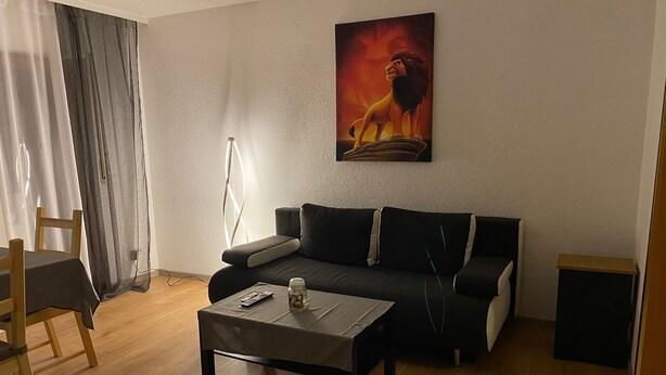 A living room with a sofa, coffee table, and a painting on the wall.
