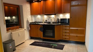 A kitchen with wooden cabinets, a stove, a microwave, and a window overlooking the kitchen.