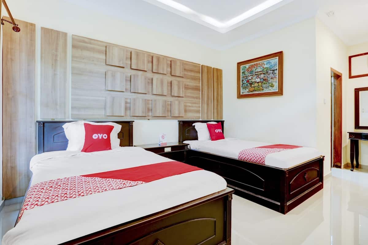 A hotel room with two beds, a wooden headboard, a painting on the wall, and a small table.