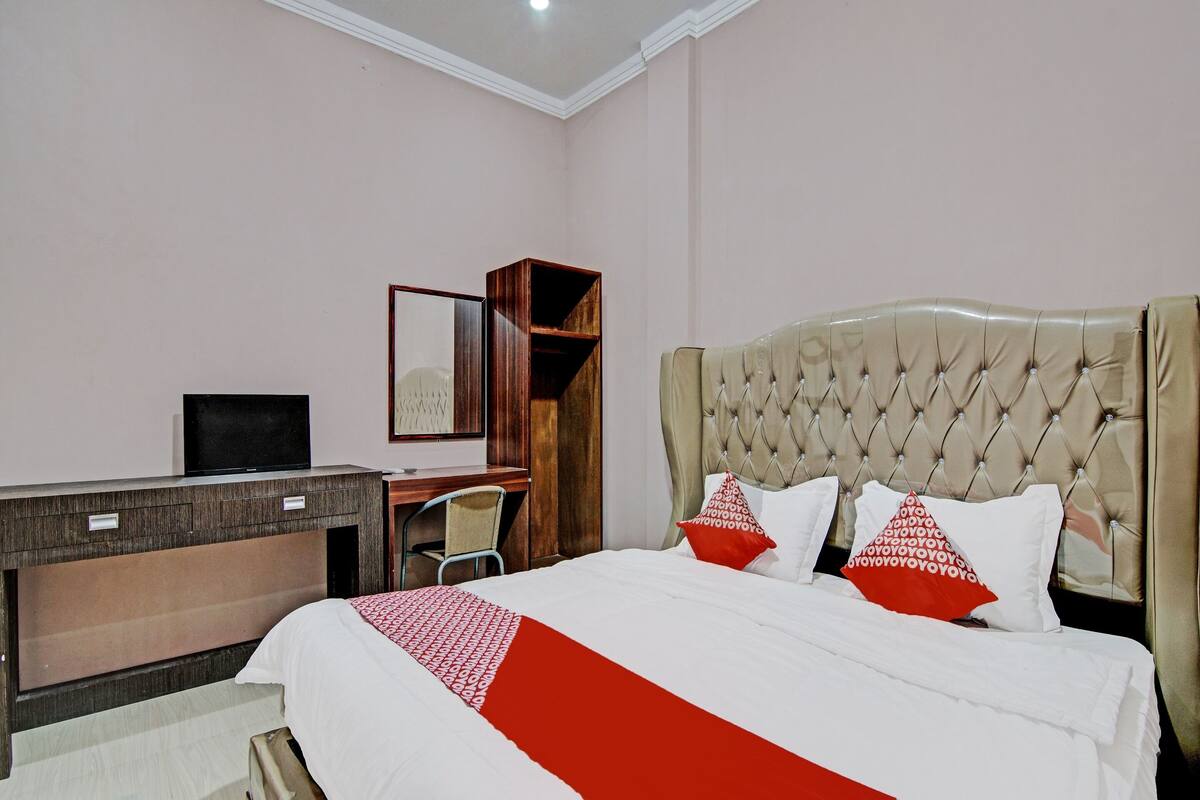 A hotel room with a bed, a desk, and a television.