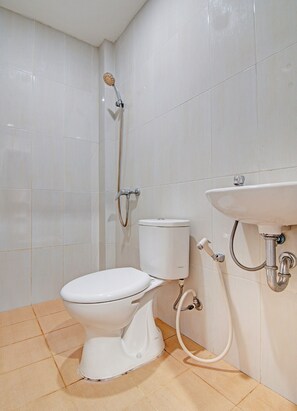 Bathroom features a toilet, shower head, and sink, with tiled walls and floors.