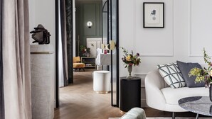 A modern living room with a sofa, a coffee table, and a side table. There is a framed picture on the wall and a plant on the side table. - Palacio Arriluce Hotel (Getxo)