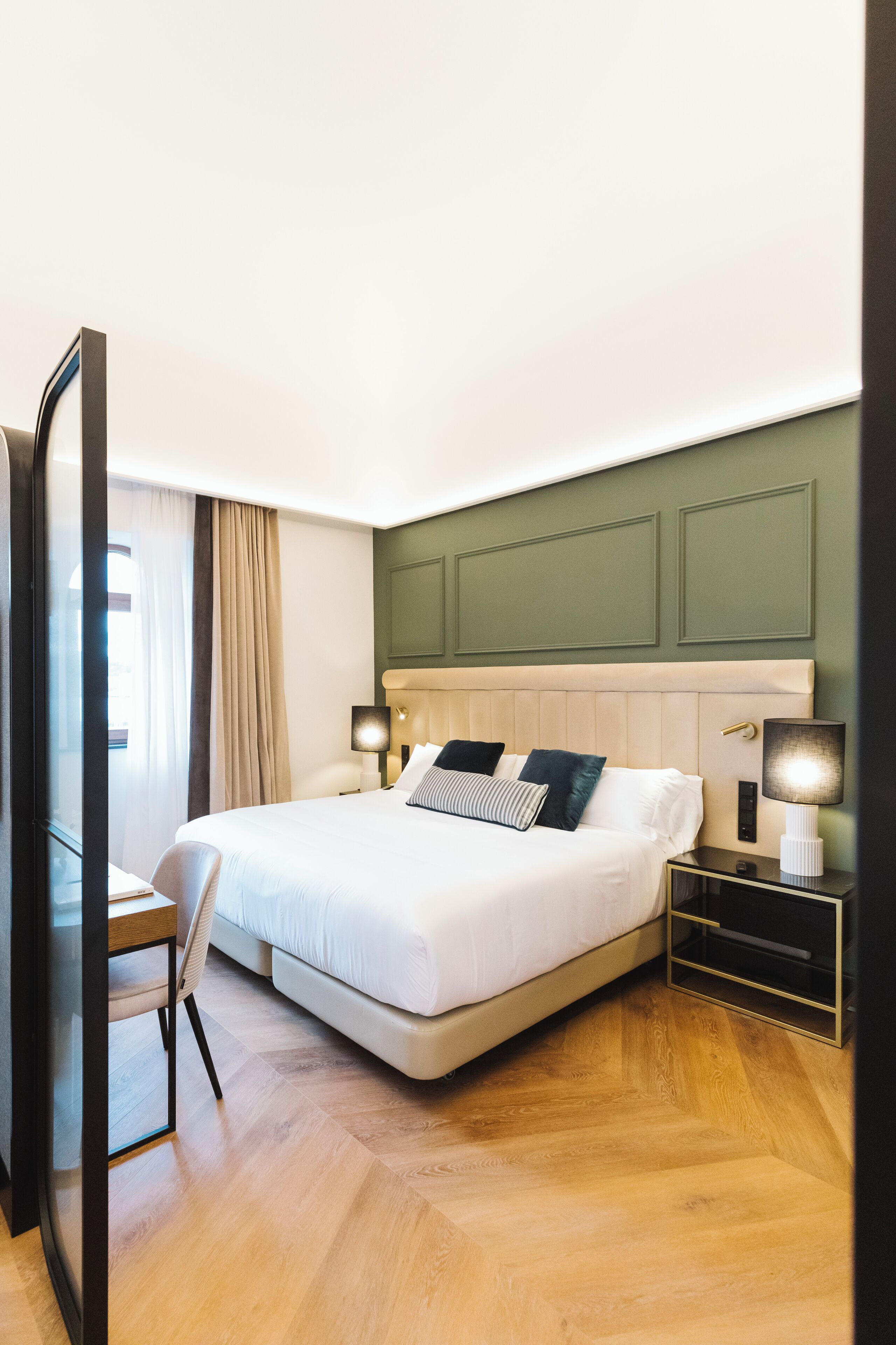 Una habitación de hotel con una cama grande, mesitas de noche, un escritorio y una silla.