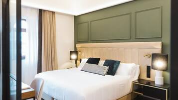 Una habitación de hotel con una cama grande, mesitas de noche, un escritorio y una silla.