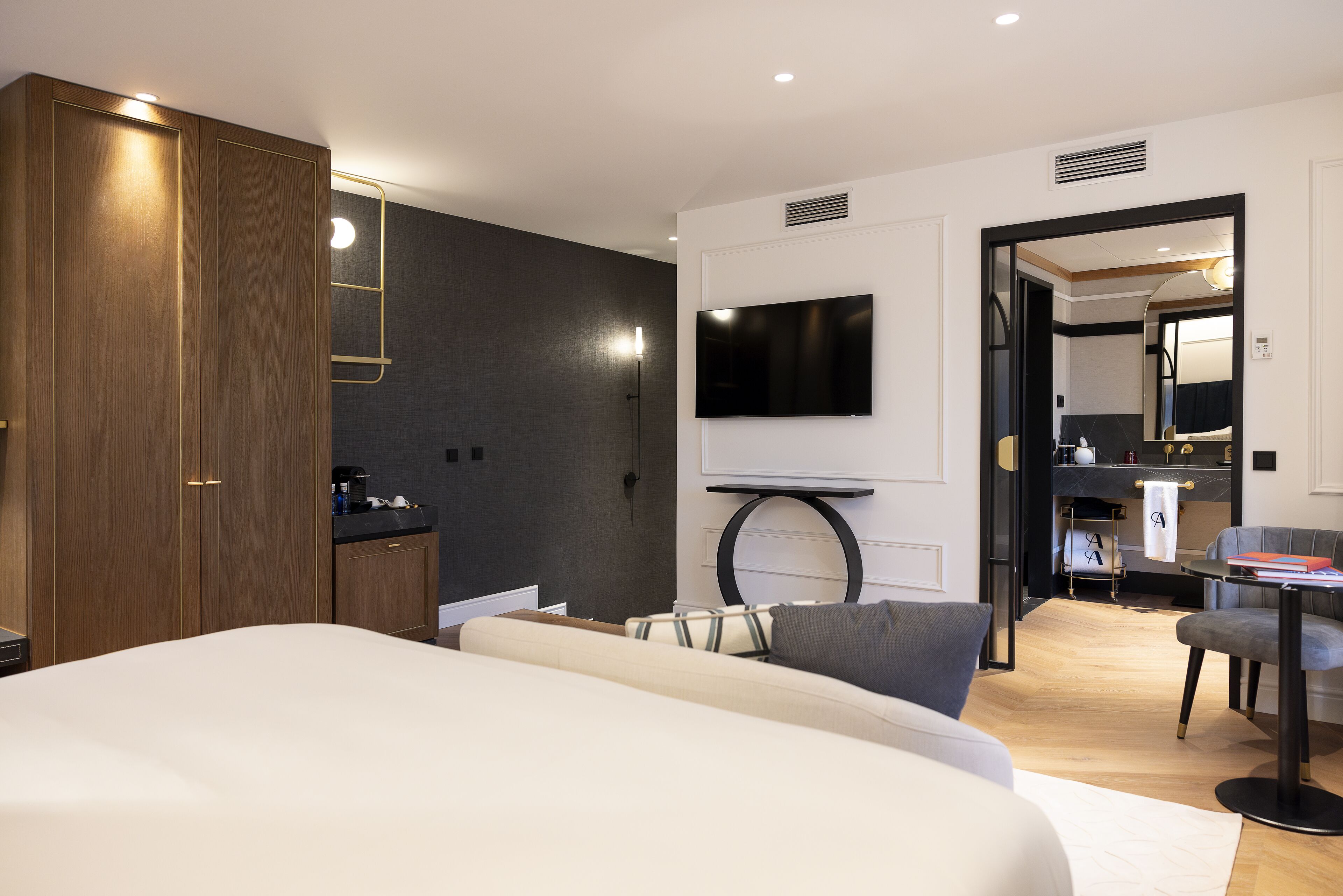 Una habitación de hotel moderna con una cama grande, un televisor de pantalla plana en la pared, un escritorio pequeño con una silla y un armario.