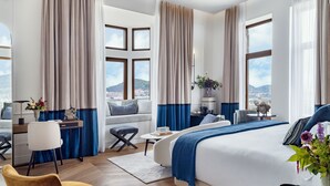 A modern hotel room with a large bed, a desk, a chair, and a view of the city. - Palacio Arriluce Hotel (Getxo)