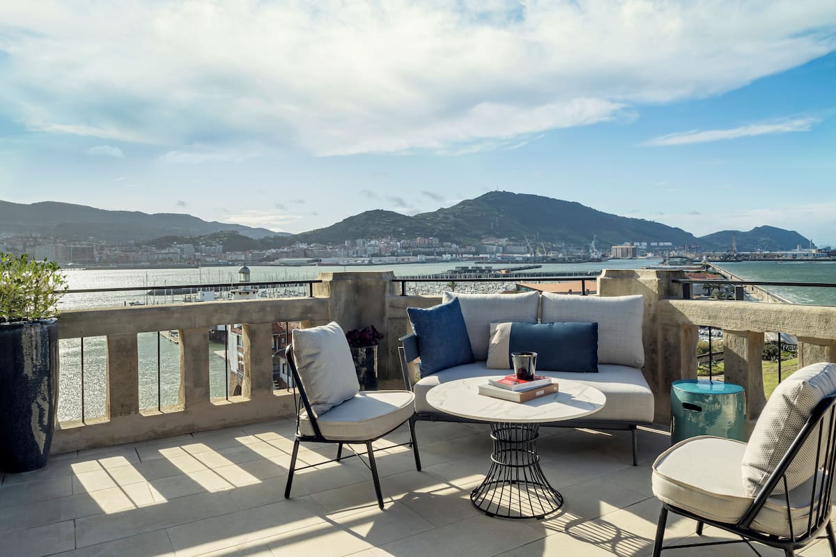 Una terraza con asientos al aire libre, vista a un paisaje urbano y un cuerpo de agua.