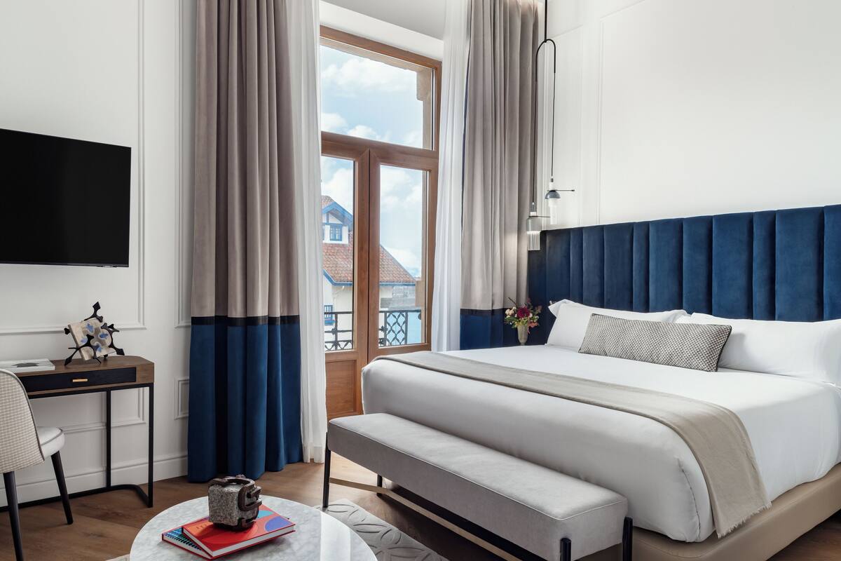 Una habitación de hotel moderna con una cama grande, un escritorio y vistas al exterior.