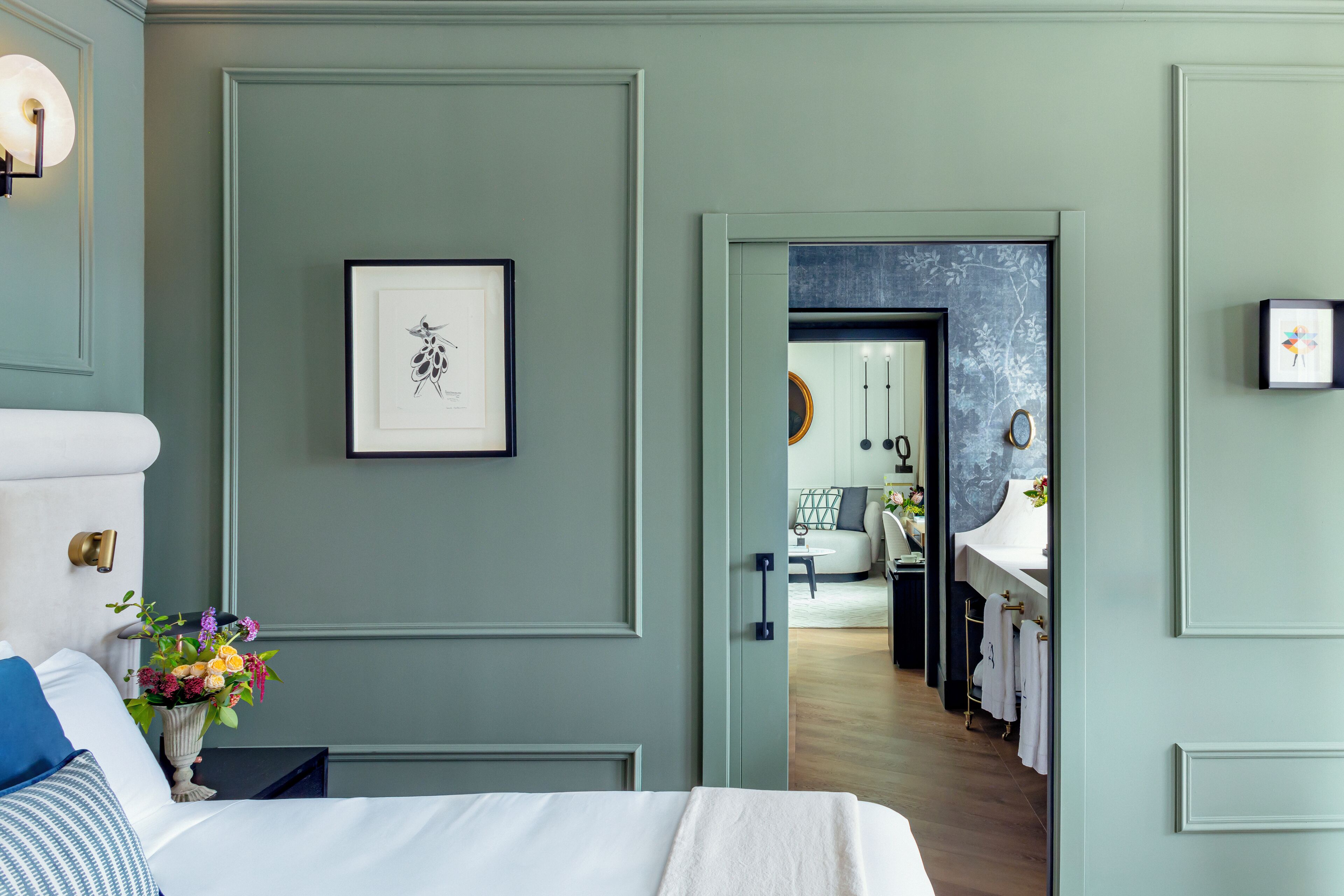 A bedroom with a bed, a nightstand, a vase of flowers, and a framed picture on the wall.