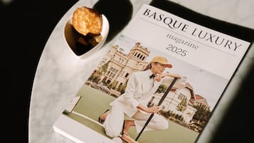 Uma revista intitulada 'BASQUE LUXURY' com uma foto de capa de uma pessoa de terno branco segurando um taco de golfe, com um edifício e vegetação ao fundo.