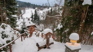 Un sentier de montagne enneigé menant à un chalet dont le toit est recouvert de neige et qui est entouré d’une clôture en bois.