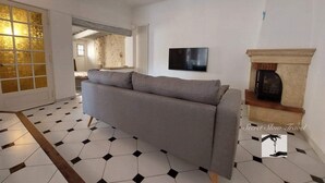 Un salon avec un canapé gris, un téléviseur fixé au mur et une cheminée.