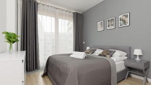 Un dormitorio moderno con una cama grande, una mesita de noche y una ventana con cortinas.