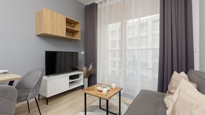 Una sala de estar moderna con un televisor de pantalla plana, una mesa de centro de madera, un sofá gris y un sillón gris.
