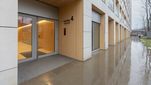 Un edificio moderno con entrada de vidrio, fachada de madera y un cartel que indica 'KLATKA 4'.