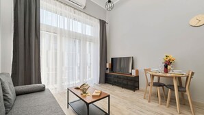 Een moderne woonkamer met een bank, een salontafel, een televisie en een eethoek met stoelen en een tafel.