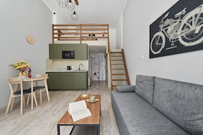 Un espace de vie compact comprenant un coin cuisine, un coin repas, un canapé et un escalier.