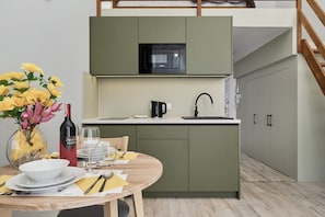 Une cuisine moderne équipée d’un four à micro-ondes encastré, d’un évier et d’un coin repas avec une table dressée pour deux personnes.