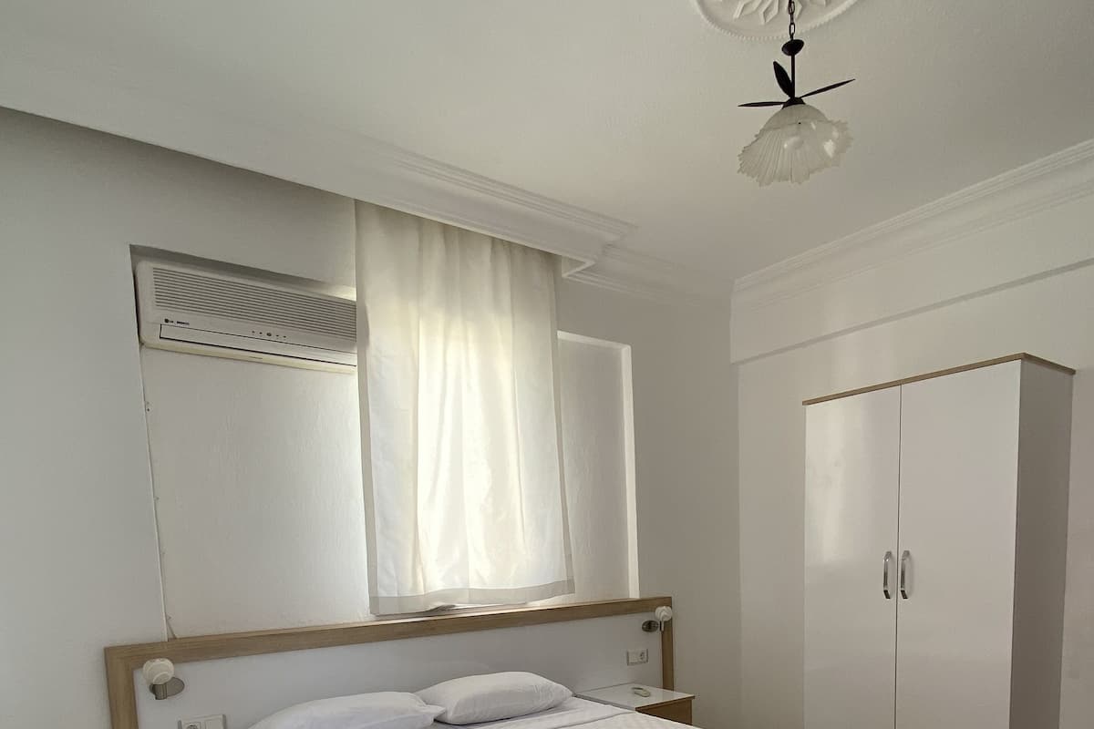 A neatly arranged bedroom with a bed, bedside tables, a wardrobe, and a ceiling fan.