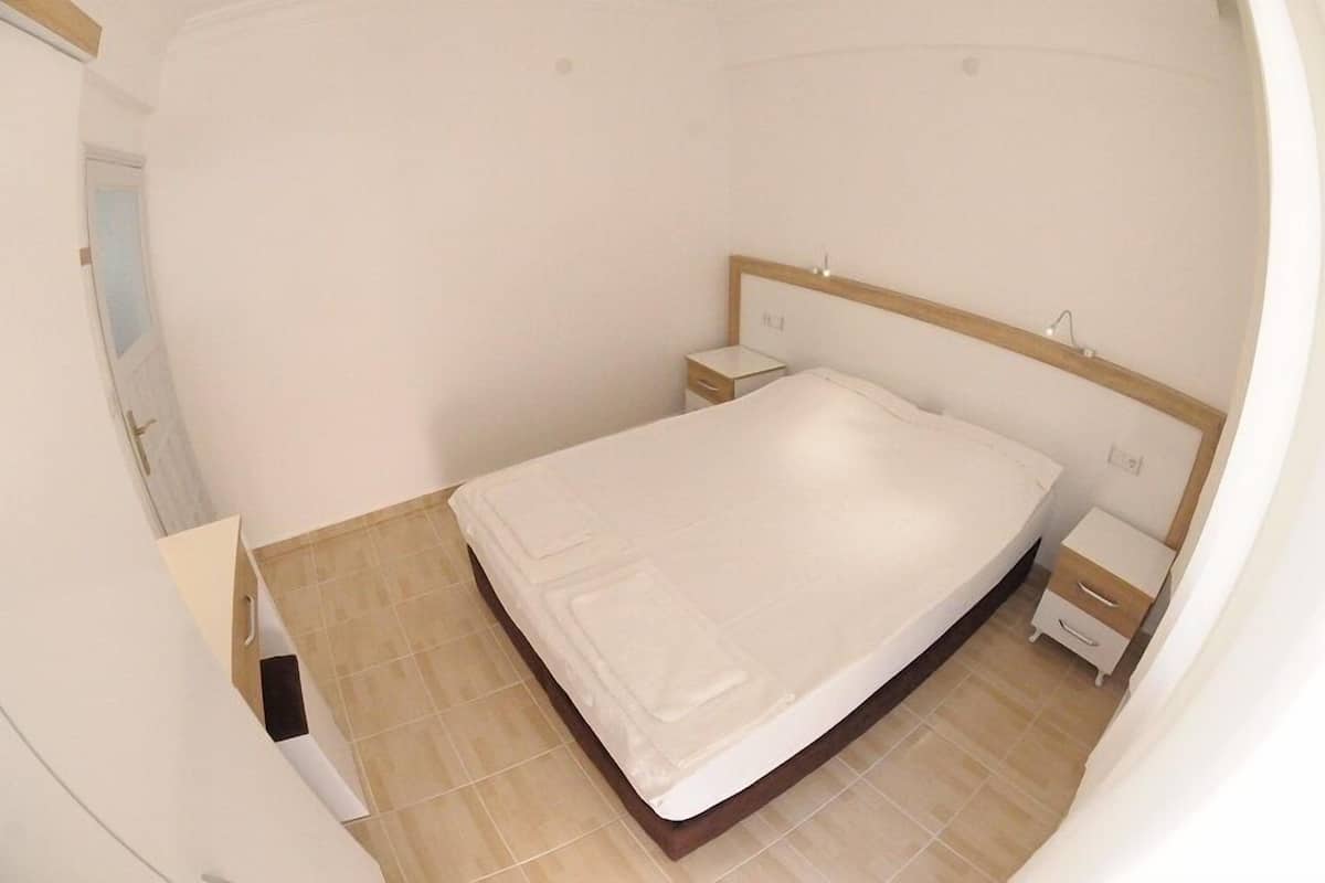 A bedroom with a bed, a nightstand, and a small drawer unit.