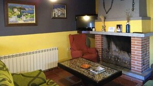 Un salon avec une cheminée, un téléviseur et deux tableaux encadrés accrochés au mur.