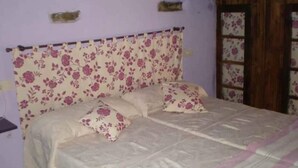 Une chambre à coucher avec une tête de lit à motifs floraux, un lit avec deux oreillers et une porte en bois.