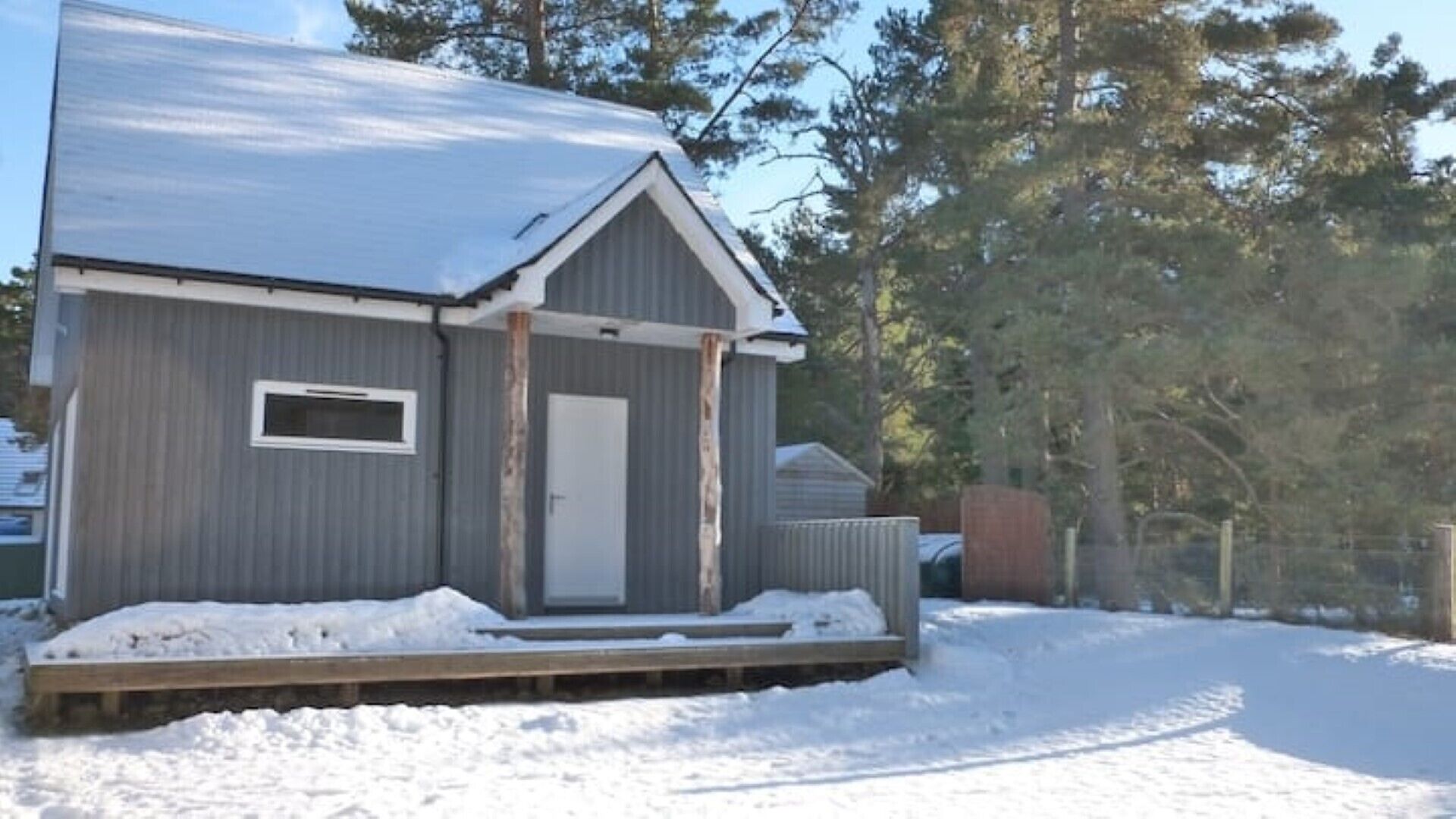 Une petite cabane à un seul étage, dotée d’un porche à l’avant et d’une fenêtre, et entourée de neige.