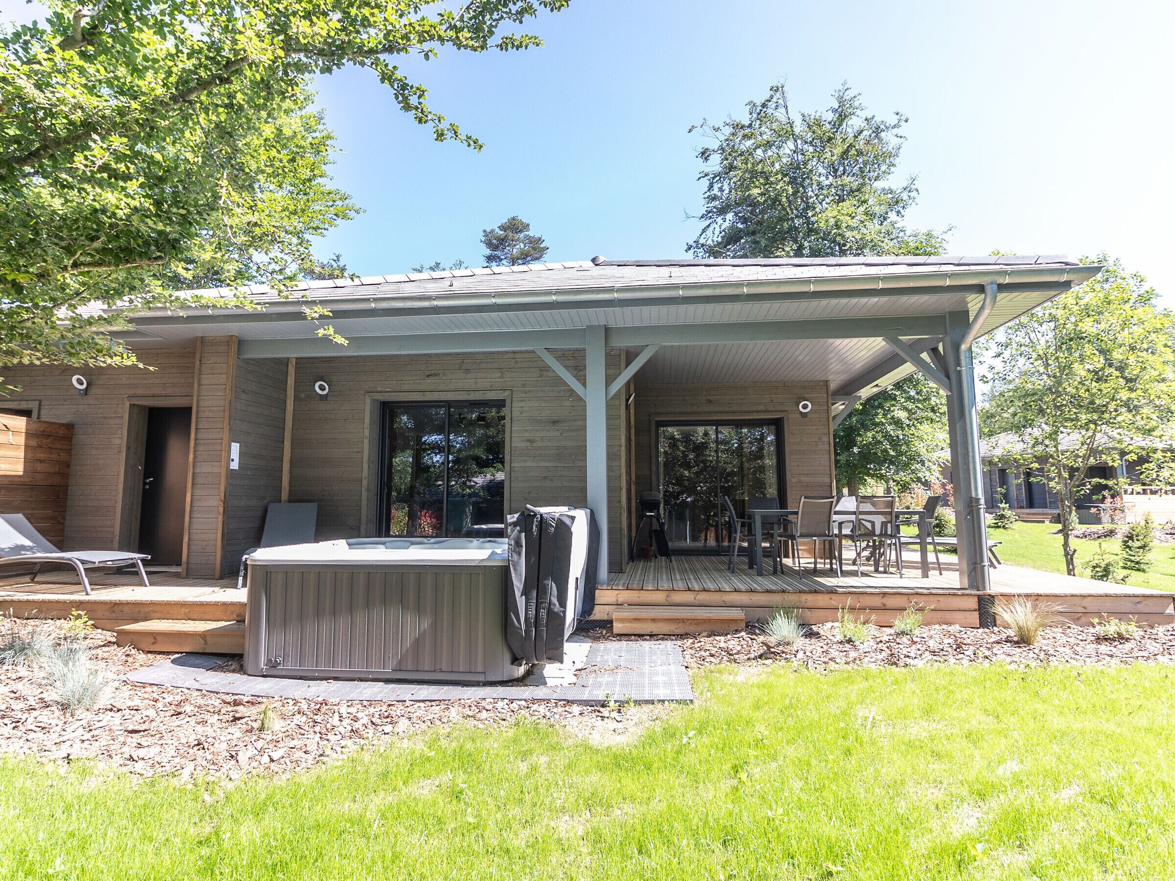 A covered outdoor area with a hot tub, seating, and a patio table.