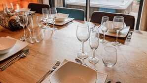 Une table à manger dressée pour un repas, avec de la vaisselle en verre, des assiettes et des couverts.