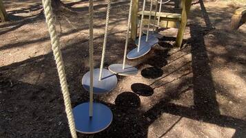 Une aire de jeux dotée d’une structure d’escalade avec des cordes et de plateformes circulaires.