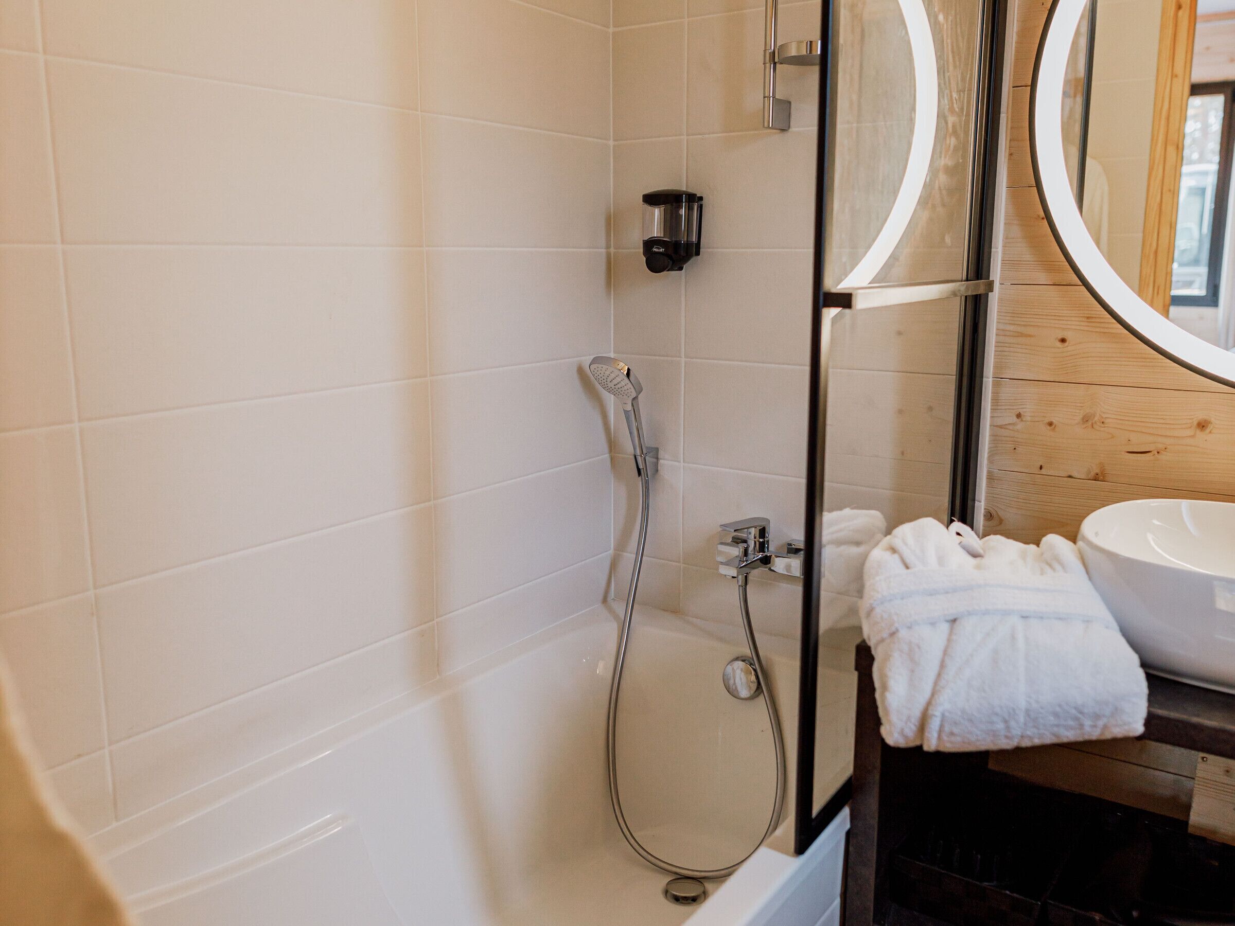 A modern bathroom with a glass-enclosed shower, a white sink, and a wooden vanity.