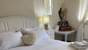 A neatly made bed with white linens, a bedside table with a lamp, and a mirror on the wall. - The Old Rectory  (Jarrow)