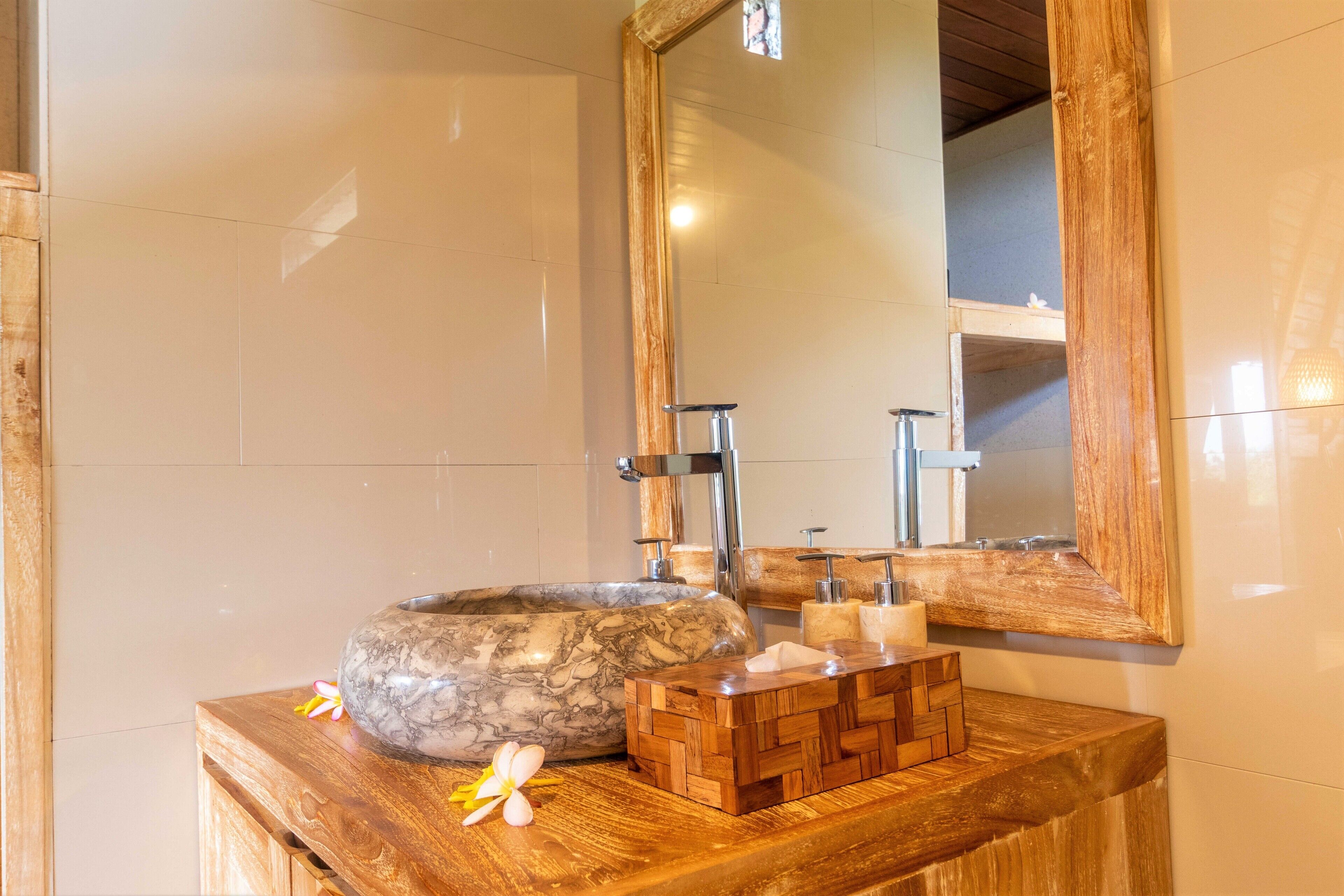 A bathroom with a marble sink, wooden vanity, and a large mirror.