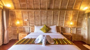 A wooden-paneled room with a bed, two bedside lamps, and a window. - AlamGangga Villas Tirta Gangga (Karangasem)