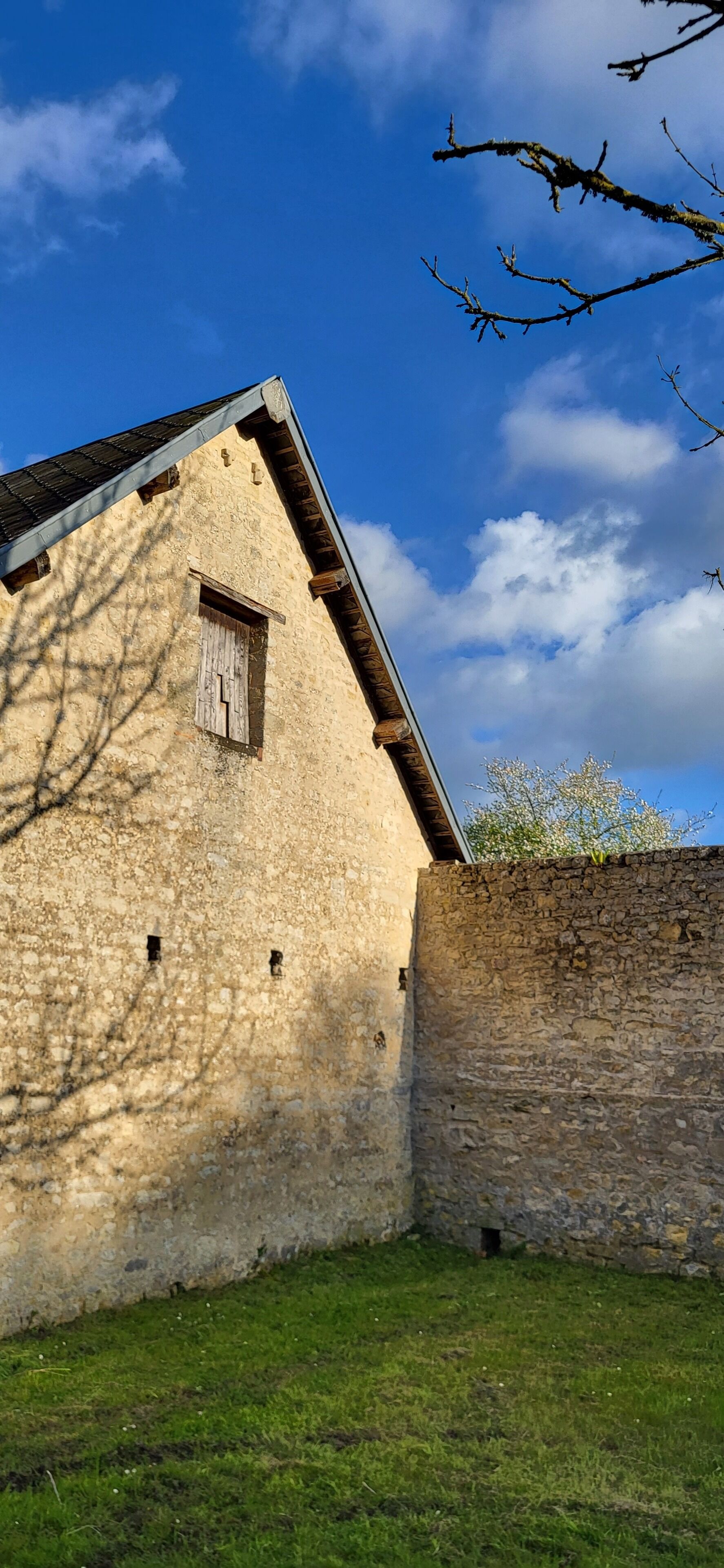 Ein Steinhaus mit geneigtem Dach und einem kleinen Fenster.