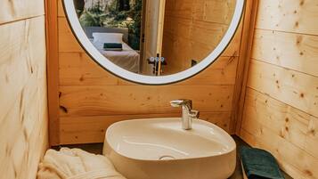 A wooden cabin bathroom with a round mirror, a sink, and a towel.