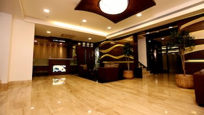 A spacious lobby with a polished marble floor, a reception desk, and a large, circular light fixture on the ceiling. - Hotel DORTN (Paud)