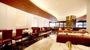 A modern restaurant with a curved ceiling, wooden paneling, and a central dining area with tables and chairs. - Hotel DORTN (Paud)