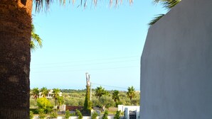 A pool with a clear view of the surrounding greenery and a white building in the background. - Case Tre Palme a San Lorenzo (Noto)