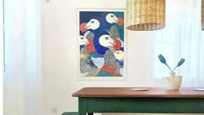 A room with a green and white table, a bench, and a painting of birds on the wall.