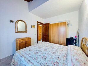 Ein Schlafzimmer mit einem Bett, einem Holzschrank und einem Spiegel an der Wand.