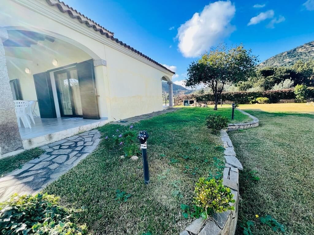 Un bâtiment doté d’un patio couvert et d’une pelouse bien entretenue, agrémentée d’un petit arbre et d’un jardin.