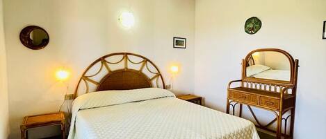 A bedroom with a bed, bedside tables, a mirror, and wall-mounted lights.